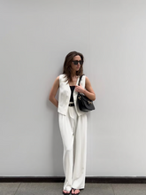 a lady wears a white pleated suit pants with a white suit vest
